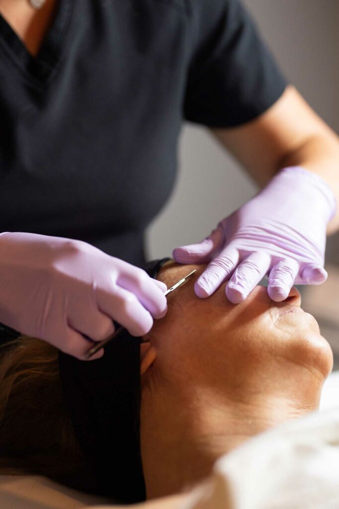 A woman receiving a facial treatment with a needle at a spa and salon.