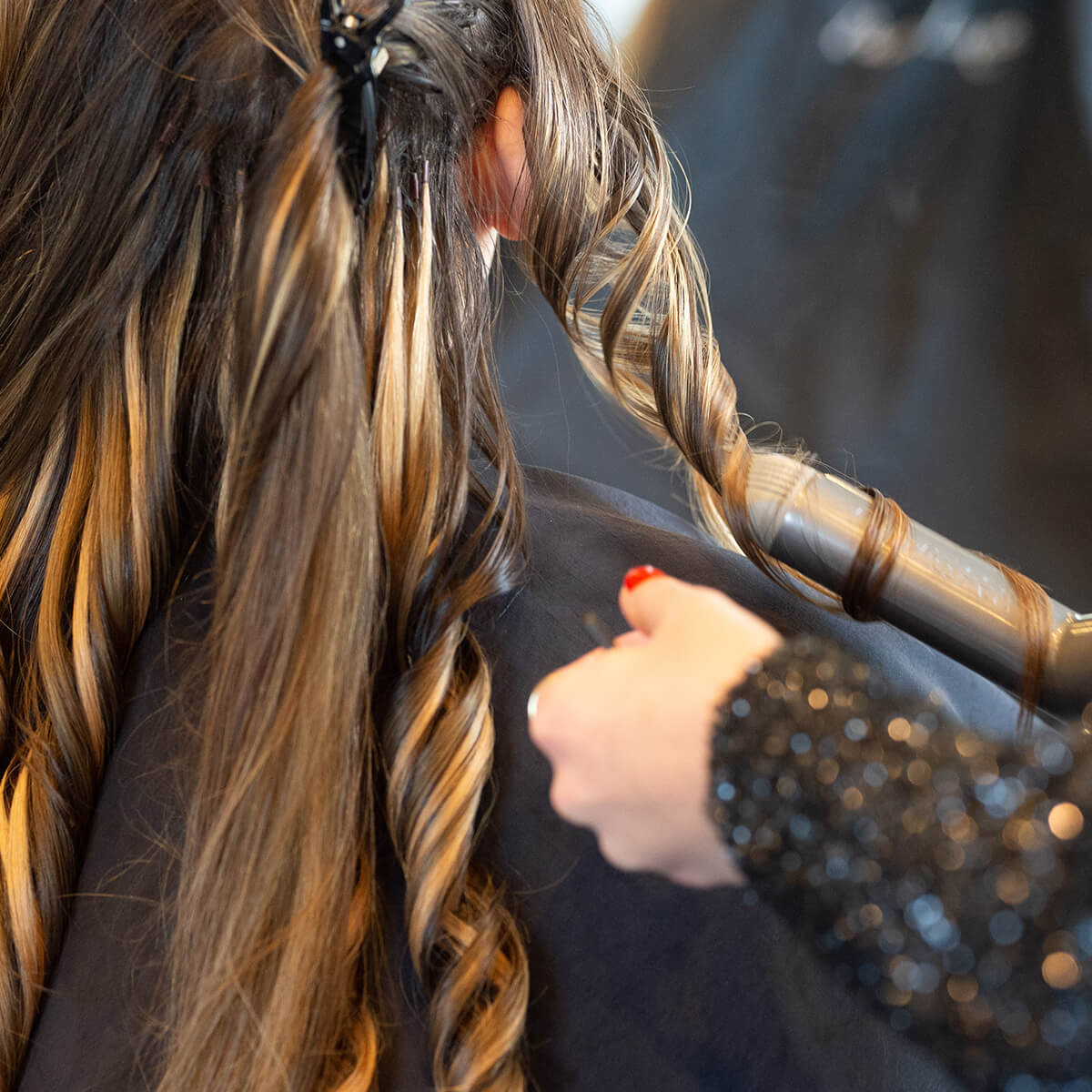 A woman at a salon having her hair styled with a blow dryer.